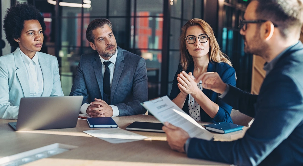 Four colleagues sat at a table in a meeting