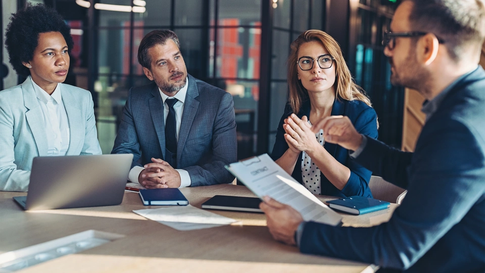 Four colleagues sat at a table in a meeting