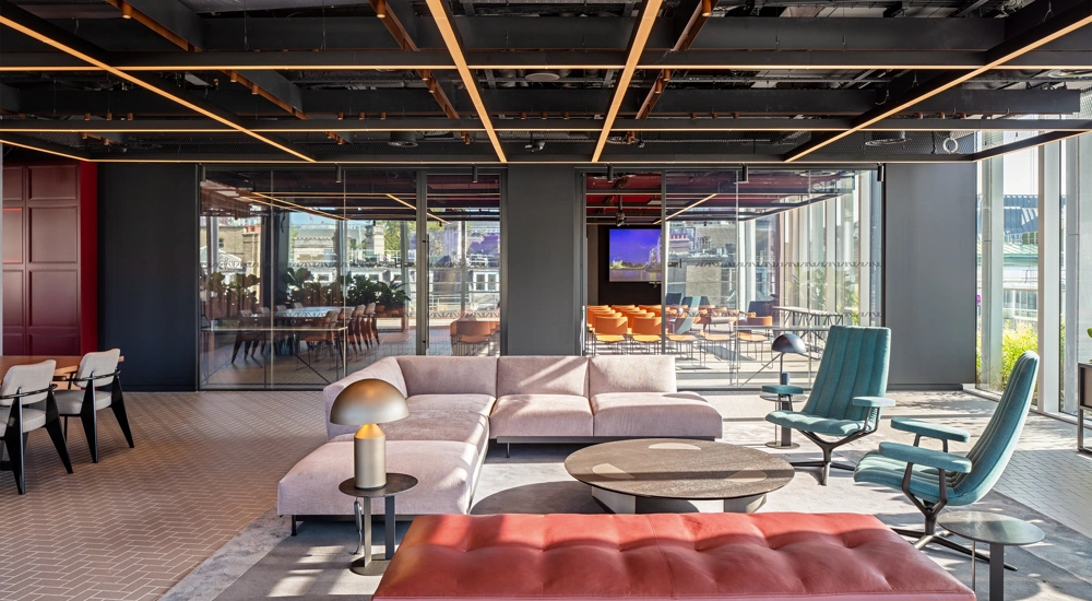 Modern, light-filled office interior with sofas in the foreground and a glass meeting room in the background