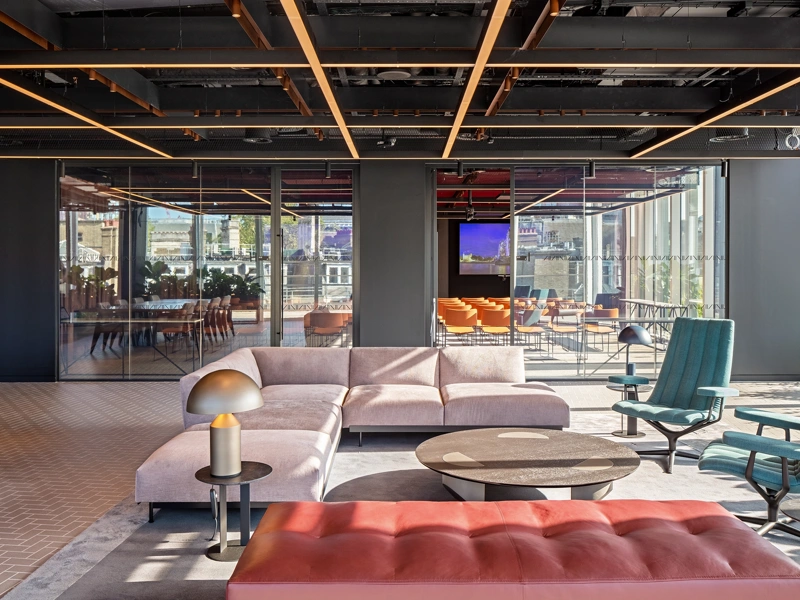 Modern, light-filled office interior with sofas in the foreground and a glass meeting room in the background