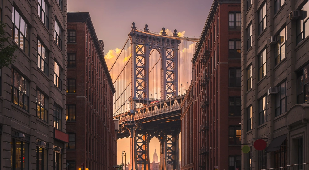 New York city street view with bridge and Empire State Building in the far distance