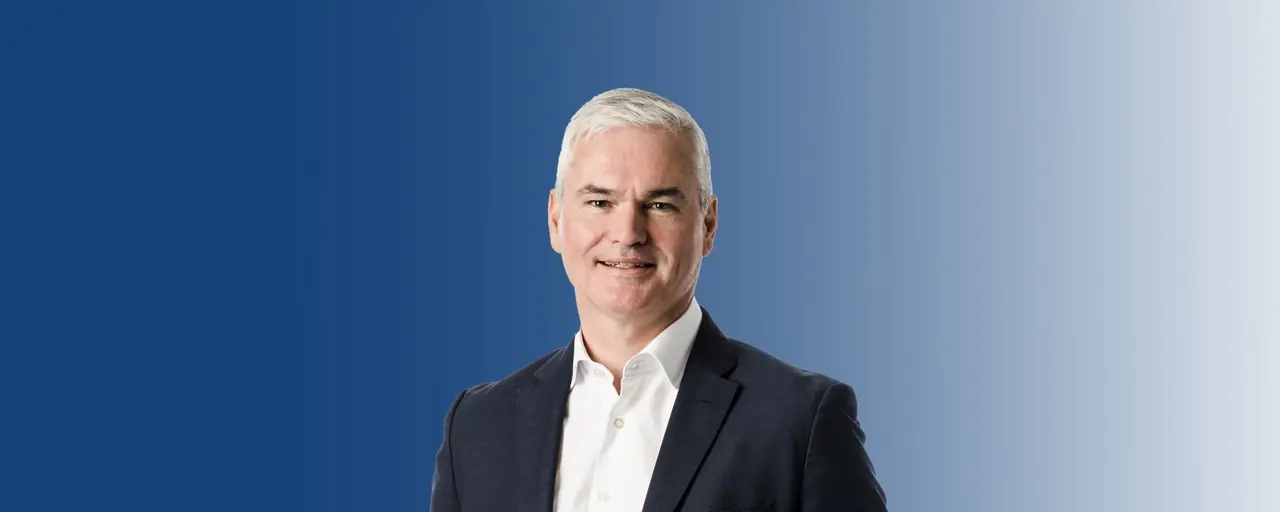 Portrait of Vincent Clancy smiling against a blue background