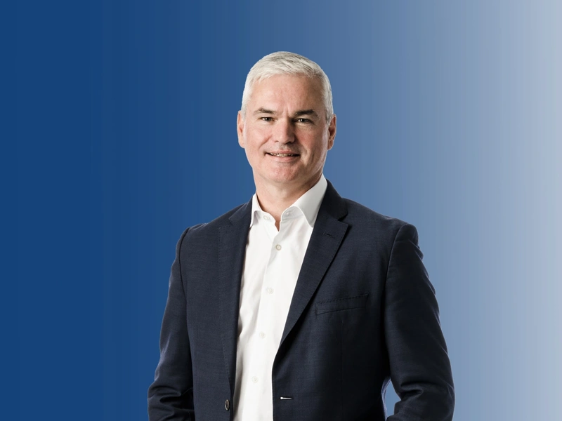 Portrait of Vincent Clancy smiling against a blue background