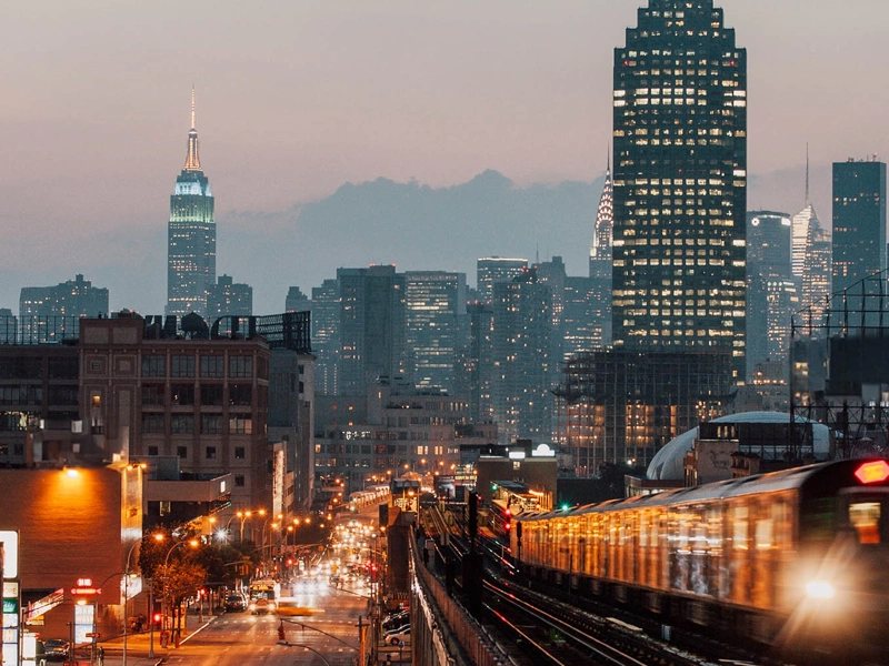 New York skyline at night with trains, skyscrapers and cars