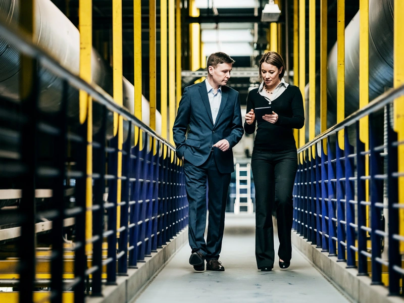 Two professionals walking through a factory