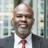 Portrait of Eric Ousoh, Senior Project Manager, with city landscape featuring building with lots of windows in the background.