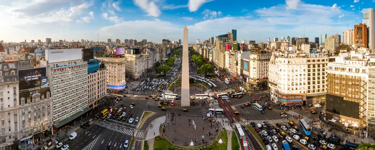 Skyline view of Buenos Aires with lots of cars on the road and tall monument in the middle 