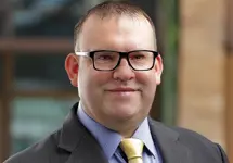 Portrait of Marc Fooks, UAE Infrastructure Lead, outside in front of a blurred brown background featuring a building and mix of natural and urban elements.