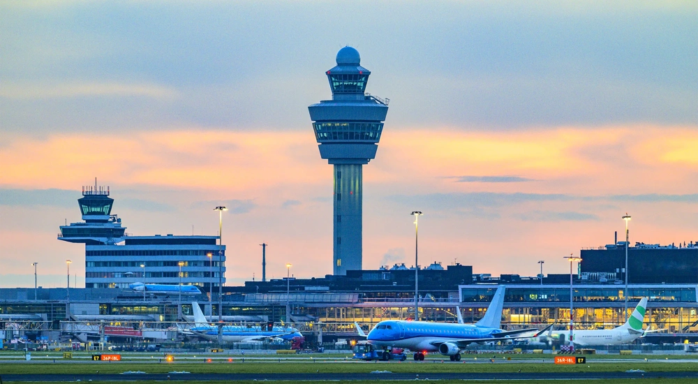 Schiphol airport with various airplanes at night. Schiphol is one of the busiest and largest airports in Europe, located near Amsterdam, Netherlands. It serves as a major hub for international flights and is a key gateway to Europe.