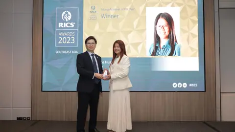 Photo of two people at an awards event, with one person receiving an award from the other person