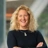 Portrait of Vicky Shepherd, Associate Director, UK Communications, standing with arms folded in office smiling