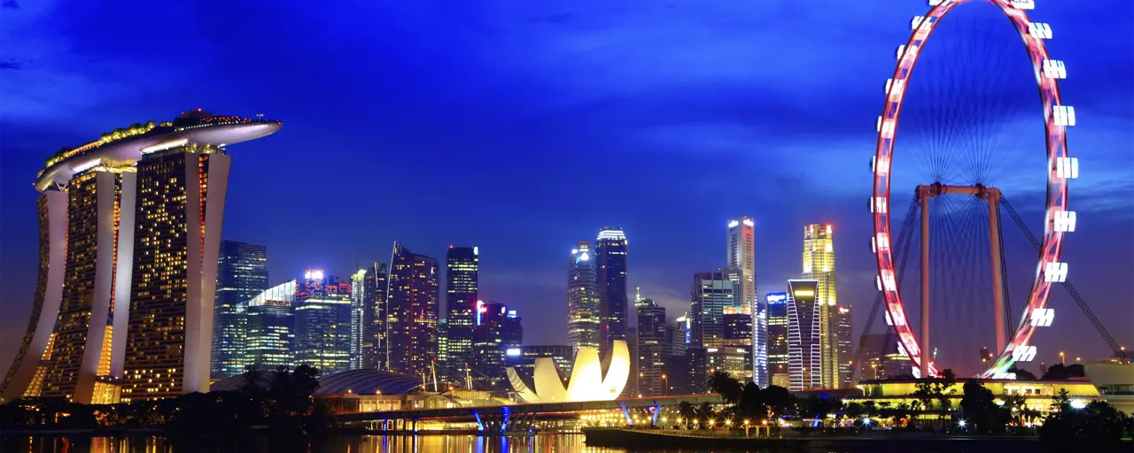 View of Singapore in the night time with the wheel lit up and Singapore skyscrapers lit up