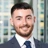Portrait of Calum Watson, Project Manager, with city landscape featuring building with lots of windows in the background.