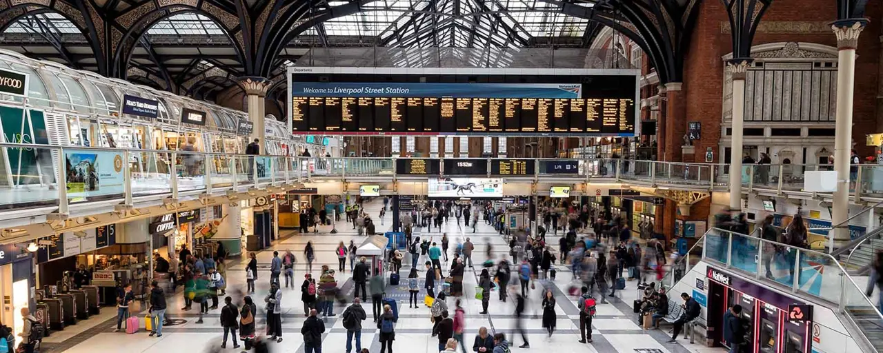 Interior photo of Liverpool Street train station in London, showing dozens of commuters walking through the station's concourse