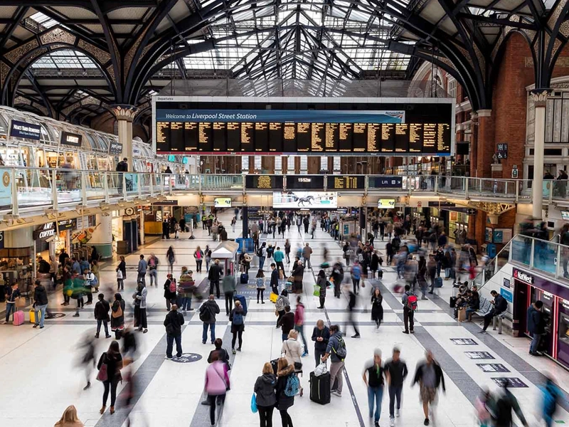 Interior photo of Liverpool Street train station in London, showing dozens of commuters walking through the station's concourse