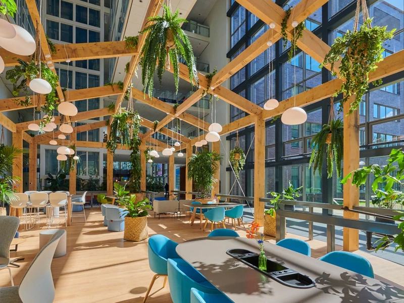 Bright interior of Shell's Energy Transition Campus with wooden beams and hanging plants, Amsterdam, The Netherlands