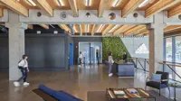 Modern Adidas offices with wooden interior and two people walking while a woman talks to a man at a reception desk