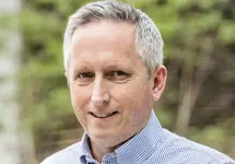 Martin Sudweeks, UK Managing Director, Cost and Commercial Management, smiling in a blue shirt outside in front of trees