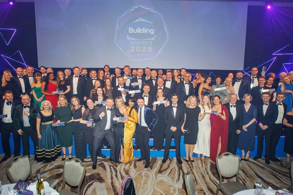 Turner & Townsend winners standing in front of billboard sign smiling at the building awards 2025