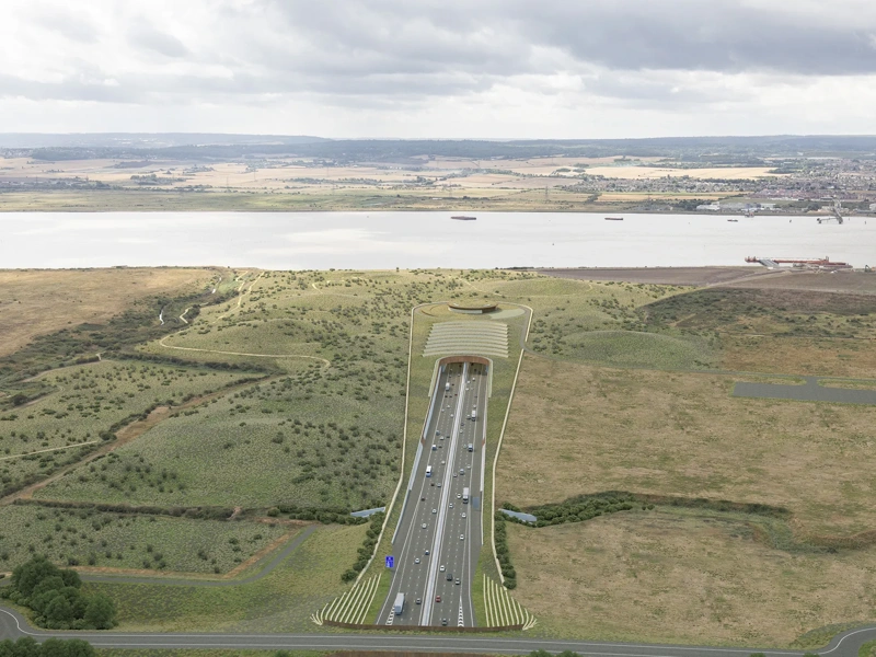 Portrait of highway surrounded by green fields and river.