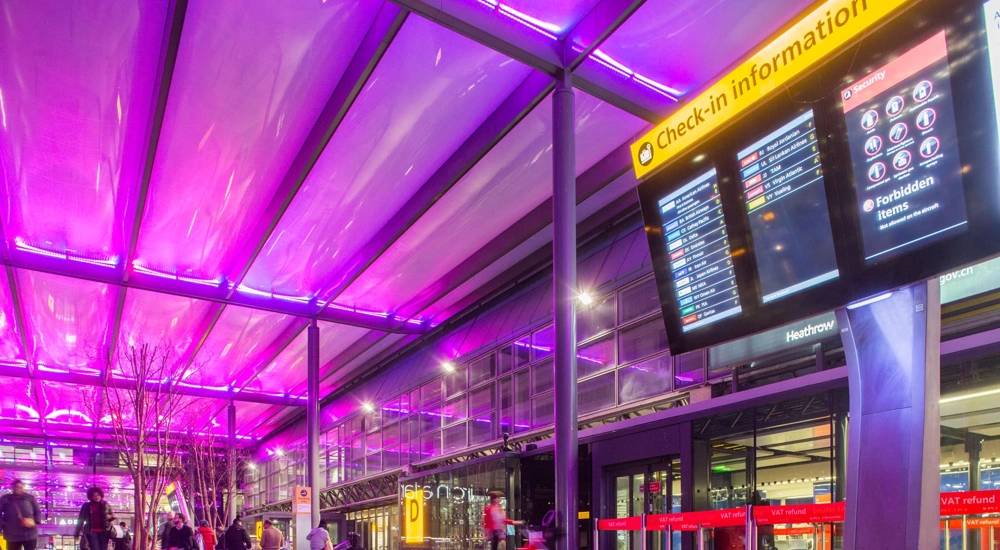 Airport terminal with purple ceiling and check-in information board