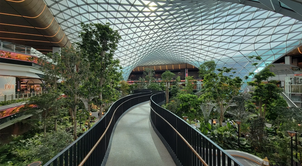 Massive glass dome and elevated walkway above indoor garden at the Orchard at Doha's Hamad International Airport