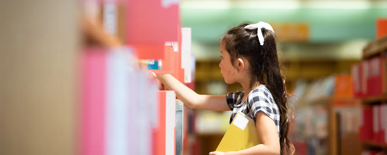 A young girl in a library looking through the books.