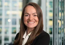 Portrait of Georgina Bishop, Associate Director, Cost Management, with city landscape featuring building with lots of windows in the background.