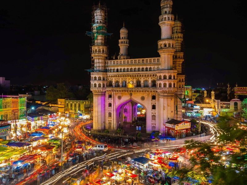 Long-exposure photo of traffic moving around the Charminar monument at night in the city of Hyderabad
