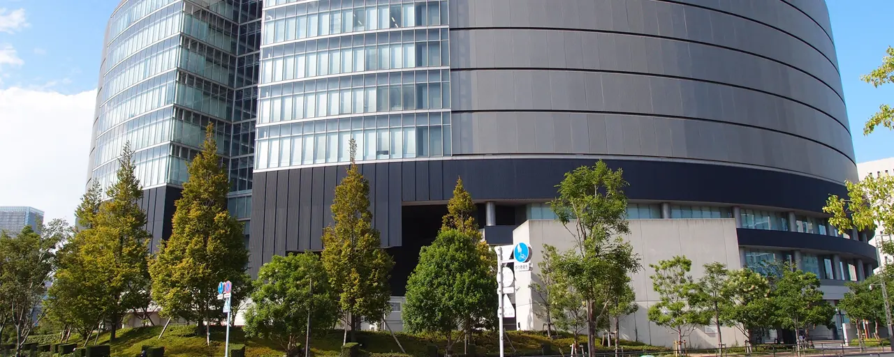 Large grey circular shaped building surrounded by green trees